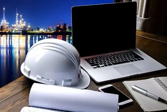 A laptop and a cap with pen paper are placing on a table
